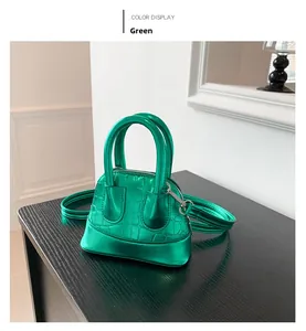 Detail view of mini shell bag in green crocodile embossed leather with silver hardware