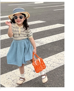 Detail of a bright orange handmade beaded handbag paired with a summer knit girl's outfit