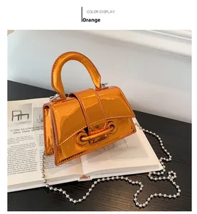 Close-up of orange mini handbag with glossy finish and silver beaded chain strap