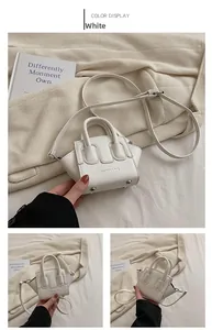 Dettaglio mini borsa bianca con tracolla regolabile e piedini protettivi in metallo