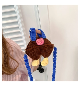 Detail of handmade crochet cartoon crossbody bag with blue straps and brown yarn texture