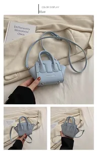 Dettaglio della mini borsa blu in similpelle con borchie e scritte moda sul fronte