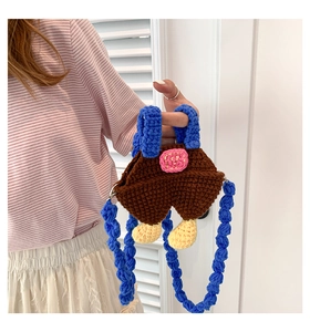 Detail of handmade crochet mini bag with cartoon overall design and blue shoulder strap