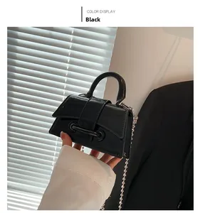 Detail of glossy black patent leather mini handbag with stylish metal ball chain strap