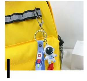 Close-up of cute astronaut keychain with blue silicone strap on yellow canvas backpack