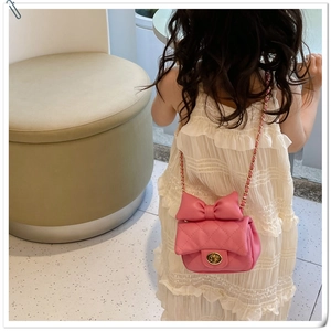 Detail of pink quilted girl's crossbody bag with bow decoration and chain strap