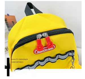 Detail of yellow canvas backpack showing dual black zippers and red fashion bag pullers