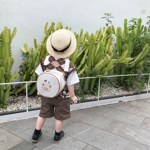 Sac à dos enfant mignon en toile avec broderie d'ours présenté dans un cadre extérieur
