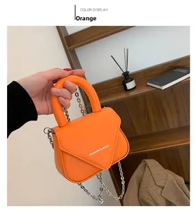 Details einer orangen Lederumhängetasche mit Silberkette und V-Klappen-Design