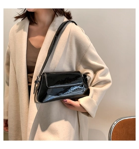 Detail einer glänzenden schwarzen Lackleder-Schultertasche mit feinen Nähten am Mantel