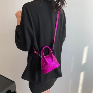 Mini shell crossbody bag in metallic magenta crocodile pattern with model background