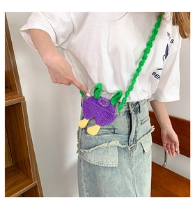 Detail view of a handmade purple knit crossbody bag featuring funny yellow feet and green leaf