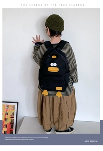 Side view of kid wearing a cartoon duck backpack with durable black canvas and 3D details
