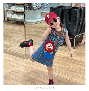 Girl wearing a handmade crochet clown crossbody bag with red hair and blue body details