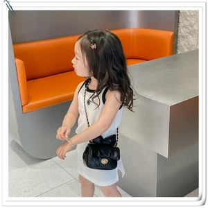 Detail of girl's black quilted mini bag with oversized bow and golden chain strap