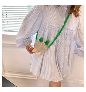 Detail of a handmade crochet cartoon crossbody bag in cream with green shoulder straps