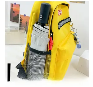 Detail of yellow canvas backpack showing side mesh pocket with folding umbrella and astronaut charm