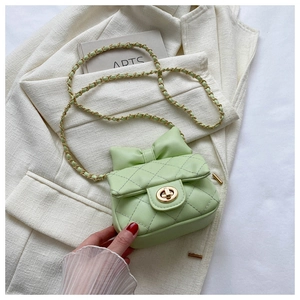Close-up of mint green quilted crossbody bag with golden chain and bow detail