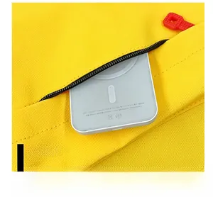 Detail showing bright yellow canvas backpack front pocket with a small white power bank