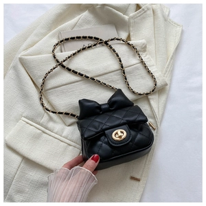 Close-up of black quilted mini bag with oversized bow and golden twist lock detail