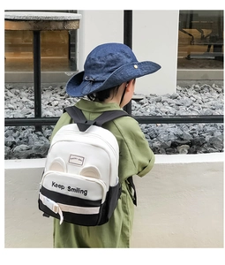 Kid's canvas backpack with cat ears and Keep Smiling print shown in an outdoor setting