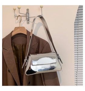 Detail einer silbernen Umhängetasche mit Spiegel-Effekt und braunem Blazer kombiniert