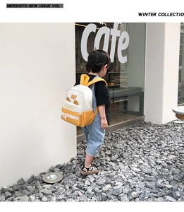 Outdoor shot of a toddler wearing a cute yellow canvas backpack with bear ears