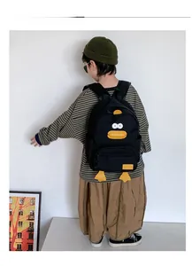 Detailed back view of kids cartoon duck backpack with yellow feet on a black canvas