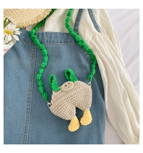 Close-up of handmade crochet mini bag featuring quirky overall pants design with green strap