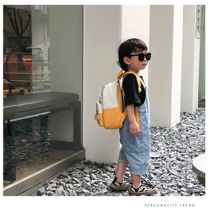 Detail view of a yellow and white canvas backpack for kids with adjustable straps