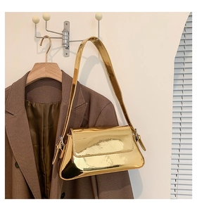 Detail einer glänzenden goldfarbenen Schultertasche mit Spiegeleffekt auf Holzbügel