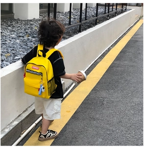 Detail of yellow kids canvas backpack with safety reflective strip and astronaut charm