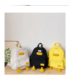 Detailed view of yellow, black, and white cartoon duck backpacks on a wooden surface