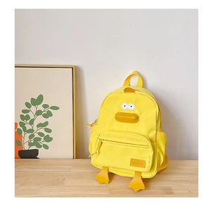 Detail of a yellow cartoon duck backpack with 3D beak and feet on a wooden desk