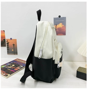 Side view of black and white canvas school backpack showing side pockets and dual zippers