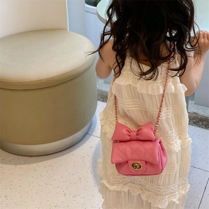 Pink quilted crossbody bag for girls with large bow and gold chain strap on model