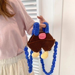Handmade brown crochet crossbody bag for kids with blue shoulder strap and pom-pom details