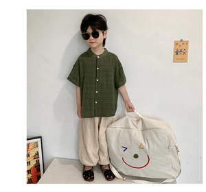 Gros plan sur chemise à carreaux vert foncé pour enfant et pantalon beige de style épuré