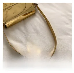 Detailansicht der goldenen Umhängetasche mit Spiegeleffekt und metallischen Gurt-Details