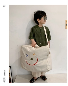 Détail d'un grand sac en toile crème avec un motif de visage souriant coloré pour enfant