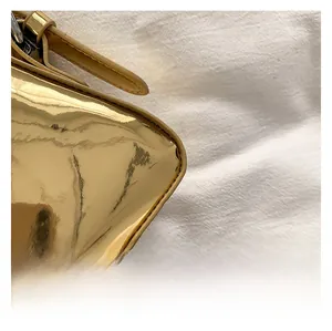 Nahaufnahme der goldenen Handtasche mit glänzendem Kunstleder und feinen Nähten am Griff