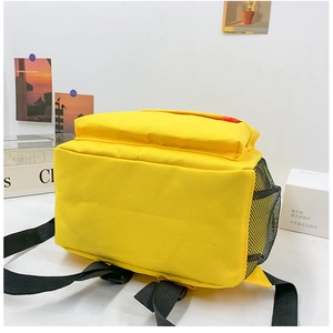 Detail view of bright yellow canvas backpack with black mesh side pocket and sturdy bottom