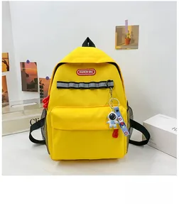 Detail of yellow canvas backpack with reflective tape and astronaut charm