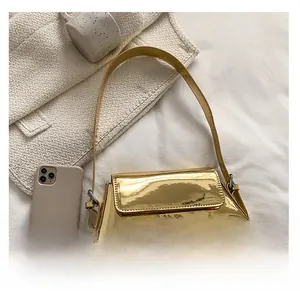 Detailansicht der goldfarbenen Lacktasche neben einem Smartphone zum Größenvergleich