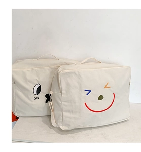 Détail de sacs en toile blanche pour enfants avec broderies souriantes et fermetures éclair
