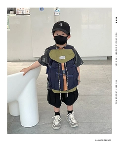 Détail du sac à dos enfant minimaliste en toile marine et verte porté par un garçon
