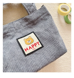 Close-up of grey corduroy kids bag featuring a cute cartoon bear embroidery patch