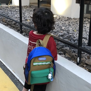 Kids color-block canvas backpack in blue and green with astronaut charm on a child's back