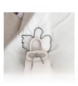 Detailed macro view of the silver rhinestone bow on a cream-colored leather mini bag