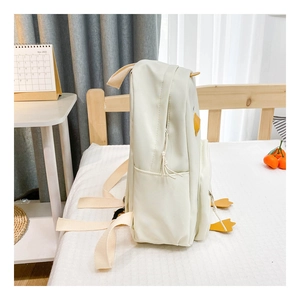 Detailed side view of a cream canvas duck backpack for kids with a storage pocket